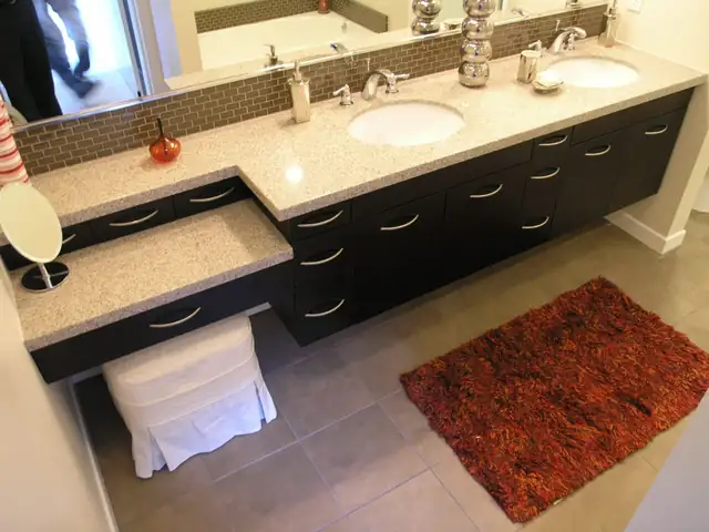 Bathroom remodel with a dark double vanity, quartz top, built-in makeup counter and glass tile backsplash
