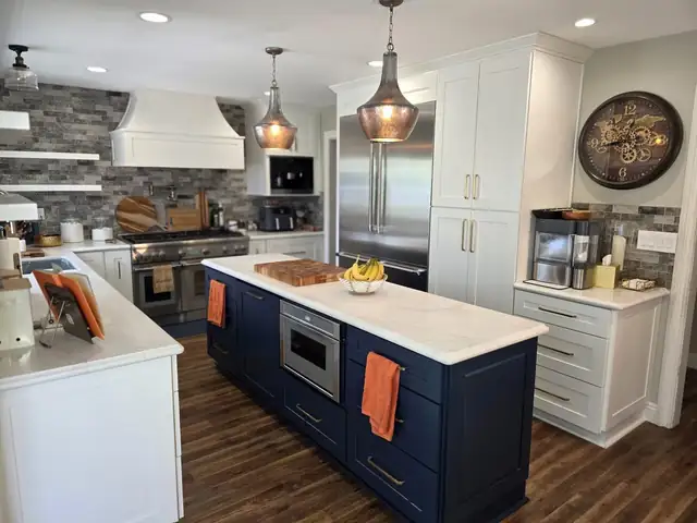 Remodeled kitchen with white cabinets, a navy blue island, white range hood and brick-look backsplash