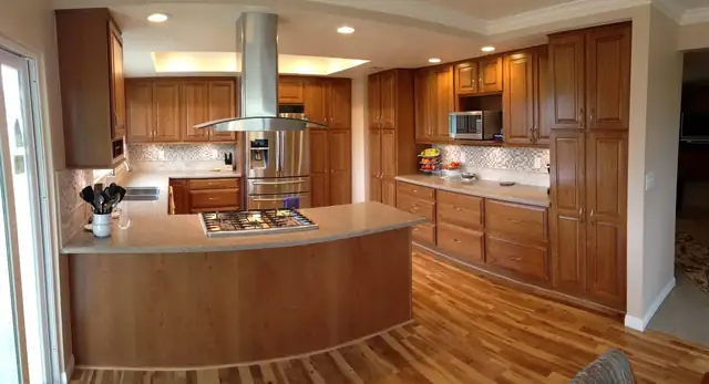 Fullerton home remodel kitchen with warm wood cabinets, a curved island and a stainless island hood