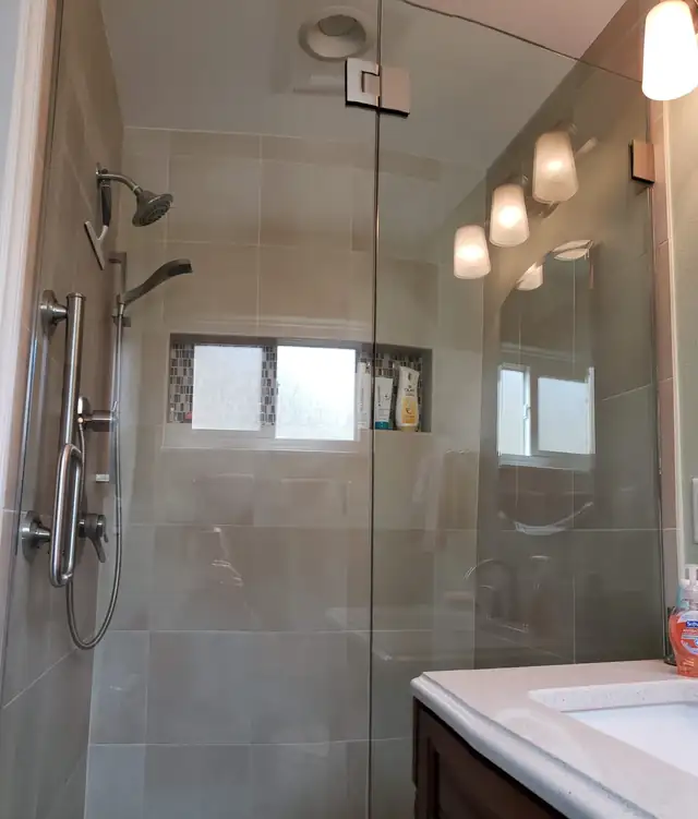 Bathroom remodel with a frameless glass shower, handheld shower bar and tiled window niche